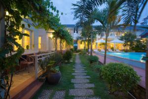 a garden with palm trees and a swimming pool at Blue Paradise Bungalow Phu Quoc in Phu Quoc