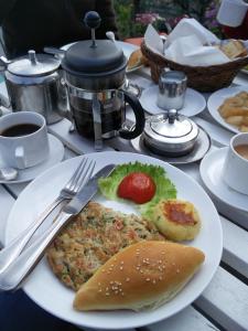 una mesa con un plato de comida con un sándwich y café en The Fort Resort en Nagarkot