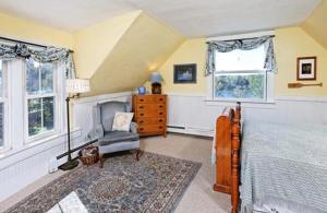 a bedroom with a bed and a chair and windows at Black Lantern B&B in Topsham