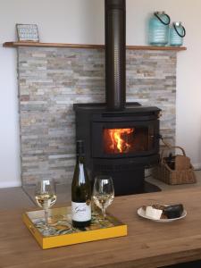 1 botella de vino y 2 copas en una mesa con chimenea en Swansea Beach House Oceanfront en Swansea