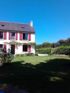 una casa con persianas rojas en un patio verde en Mme Teurtroy, Chambres d'Hôtes La Prairie, en Gouesnach