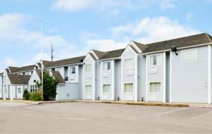 Une rangée de maisons blanches avec un parking dans l'établissement Americas Best Value Inn and Suites Ada, à Ada