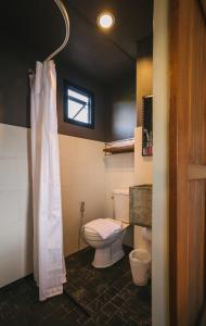 y baño con aseo y cortina de ducha. en Cozy Inn Chiang Mai en Chiang Mai