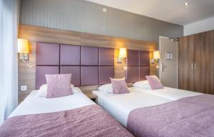 2 bedden in een hotelkamer met paarse hoofdeinden bij Hotel Victorie in Amsterdam