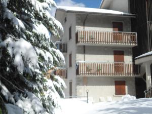 un bâtiment dans la neige avec des arbres enneigés dans l'établissement Residence Fontanelle, à Sestola