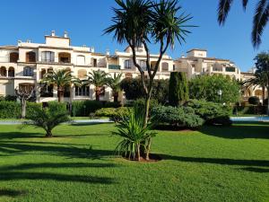 un grand bâtiment avec des palmiers dans un parc dans l'établissement JAVEA - La Isla, à Jávea