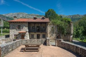 a stone house with a picnic table in front of it at Complejo Rural La Tahona De Besnes in Alles
