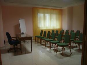 a conference room with green chairs and a podium at Hotel Centro di Spiritualità Padre Pio in San Giovanni Rotondo