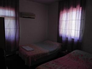 Habitación pequeña con 2 camas y cortinas rosas. en Sunrise Hotel en Antalya