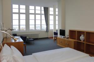 a hotel room with a bed and a tv and windows at Apartmenthaus Am Leuchtturm in Warnemünde