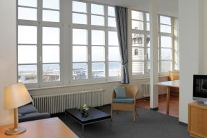 a living room with large windows and a table and chairs at Apartmenthaus Am Leuchtturm in Warnemünde