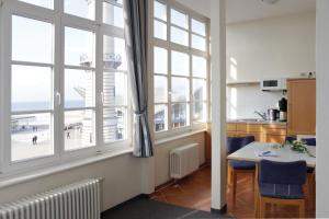 a kitchen with large windows and a table and chairs at Apartmenthaus Am Leuchtturm in Warnemünde