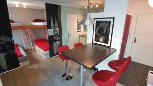 ケルンにあるアパートメント クリスチャンのテーブル、赤い椅子、二段ベッドが備わる客室です。