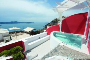 una piscina en la parte superior de una casa con el océano en Theoxenia Caldera Hotel en Fira