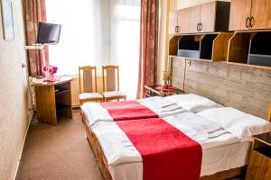 um quarto com uma cama com um cobertor vermelho e branco em Hotel Kamei em Snina