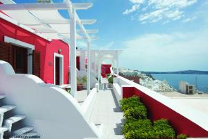 a red and white building with a view of the water at Theoxenia Caldera Hotel in Fira