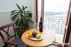 a table with a plate of fruit and a glass of water at Theoxenia Caldera Hotel in Fira