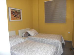 2 łóżka w pokoju z żółtymi ścianami i oknem w obiekcie A.T. Altamira 15 w mieście Bilbao