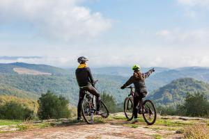 dwie osoby jeżdżące rowerami na wzgórzu z widokiem w obiekcie Villa Di Capovento w mieście Castellina in Chianti