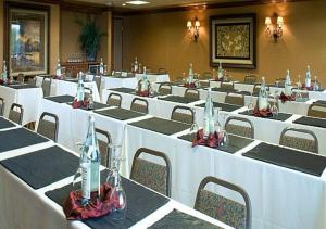 a room with tables and chairs with white tables and chairs at Grand Gateway Hotel in Rapid City