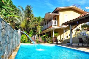a swimming pool with a water fountain in front of a house at Coco Bambu Cambury in Camburi