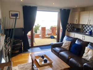 a living room with a leather couch and a table at Crud yr Awel Apartment in Y Felinheli