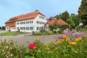 een groot wit gebouw met bloemen ervoor bij Landgasthof - Hotel Reindlschmiede in Bad Heilbrunn