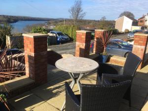a table and chairs on a patio with a view of the water at Crud yr Awel Apartment in Y Felinheli