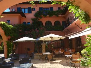 un patio al aire libre con mesas, sillas y sombrillas en Hôtel Chantaco Golf & Wellness, en San Juan de Luz