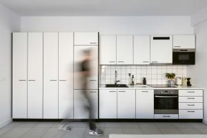 a person walking in a kitchen with white cabinets at Euryclea Residences in Athens