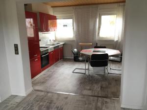 a kitchen with red cabinets and a table and chairs at KRIO Nicola Rothfuchs Ferienwohnung 1 in Idar-Oberstein +12 photos