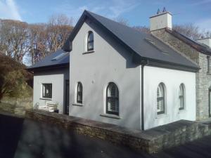 een wit huis met een zwart dak bij SunnySide-Cottage in Ennistymon