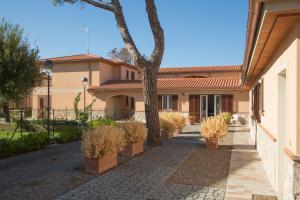 a building with a tree and a sidewalk at La Residenza del Golfo in Puntone di Scarlino