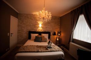 a bedroom with a large bed and a chandelier at Villa Valentino in Hasselt