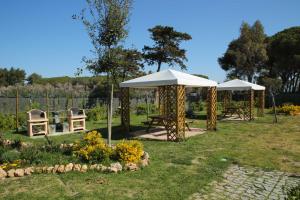 dos mesas de picnic y sombrillas en un jardín en La Residenza del Golfo, en Puntone di Scarlino