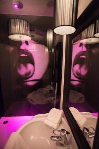 uma casa de banho com um lavatório e um espelho com iluminação roxa em Villa Valentino em Hasselt