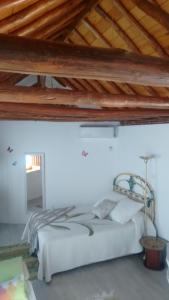 a bed in a white room with a wooden ceiling at Casa Andaluza in La Zubia