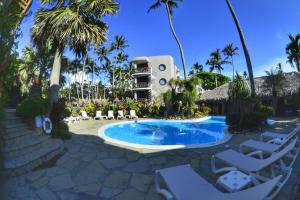 a pool at the resort with chairs and a building at El Magnifico in Cabarete