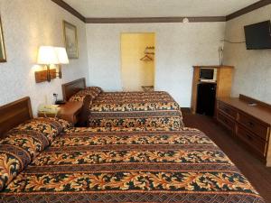 a hotel room with two beds and a television at Heritage Inn in Duncan