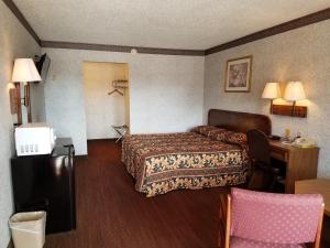 ein Hotelzimmer mit einem Bett und einem Schreibtisch in der Unterkunft Heritage Inn in Duncan