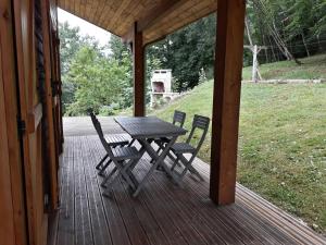 a wooden porch with a picnic table and two chairs at Le Barail 31 in Couret