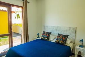 a bedroom with a bed with blue sheets and a window at Atlantica Apartamentos Imbassai in Imbassai +55 photos