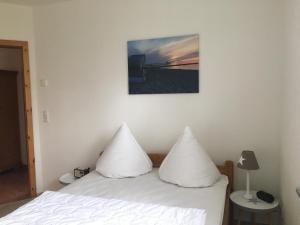 a bedroom with a bed with white pillows on it at Haus Hugo Zingst in Zingst