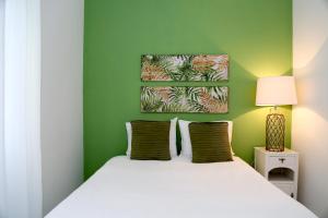 een slaapkamer met groene muren en een bed met witte lakens bij Casa do Zézêras in Nazaré