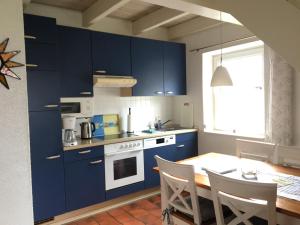 una cocina con armarios azules y una mesa con sillas en Ferienhaus Meerzeit, en Nordstrand