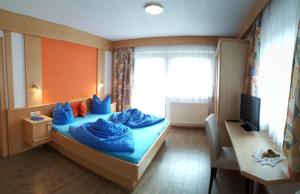 Cette chambre comprend un lit avec des draps bleus et un bureau. dans l'établissement Haus Falke, à Sölden
