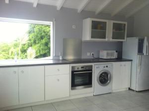 una cocina con armarios blancos y una ventana en Bois patate location, en Sainte-Anne