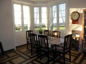 ein Esszimmer mit Tisch und Stühlen und einer Uhr in der Unterkunft Les Hautes Loignieres in Pré-en-Pail + 24 Fotos
