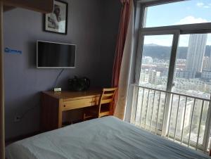 a bedroom with a bed and a desk and a window at LETE Hostel in Xining