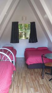 a room with two beds and a table and a window at Westport Kiwi Holiday Park & Motels in Westport